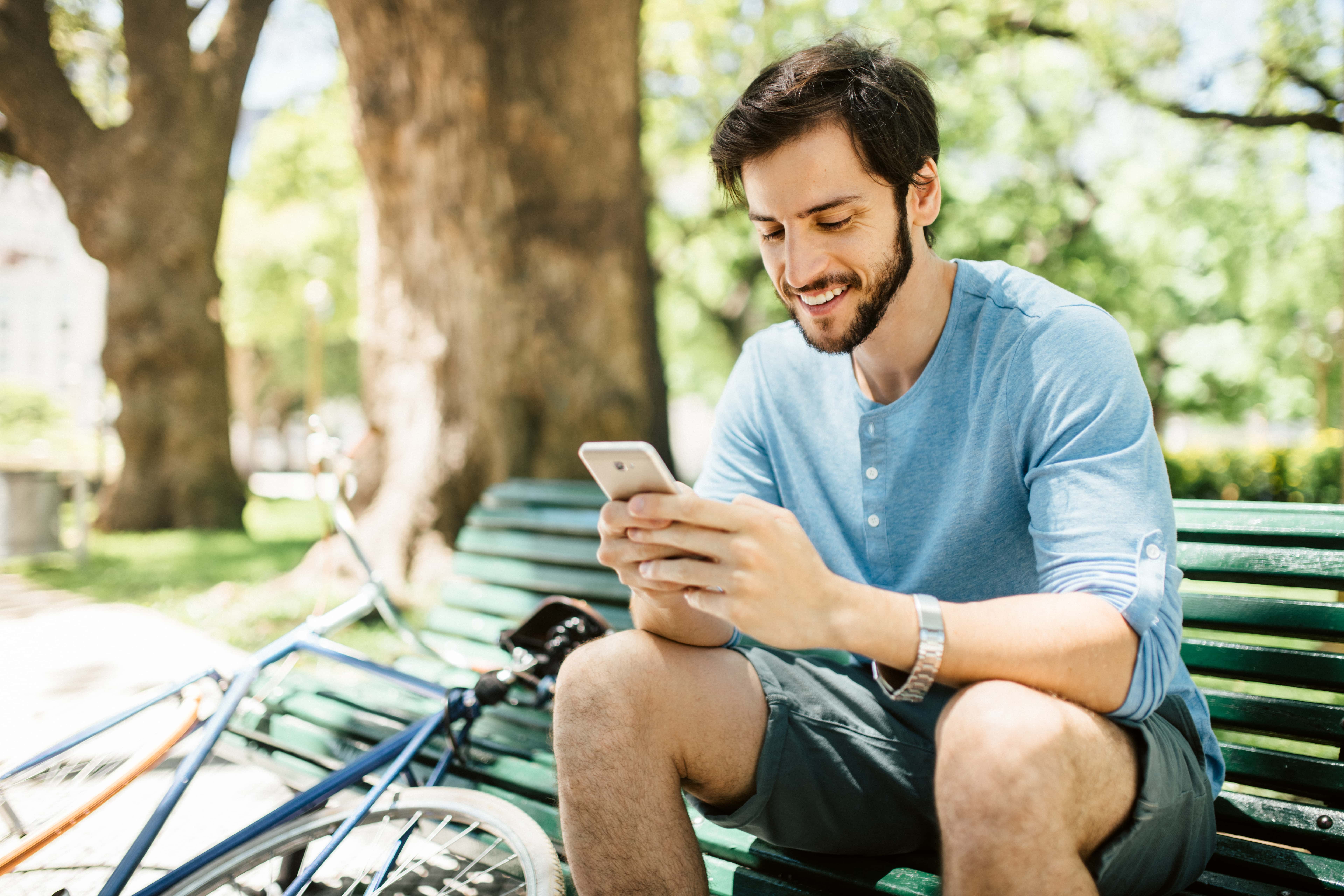 Man on park bench looking at mobile phone