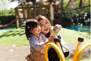 Mother and daughter having fun with bubbles in the playground on a sunny day. Mother and daughter bonding time. Family love and togetherness.