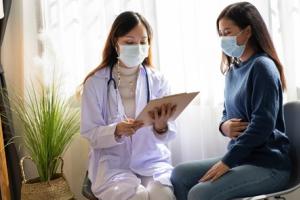 Female doctor explaining IBD awareness to a female patient clutching her stomach