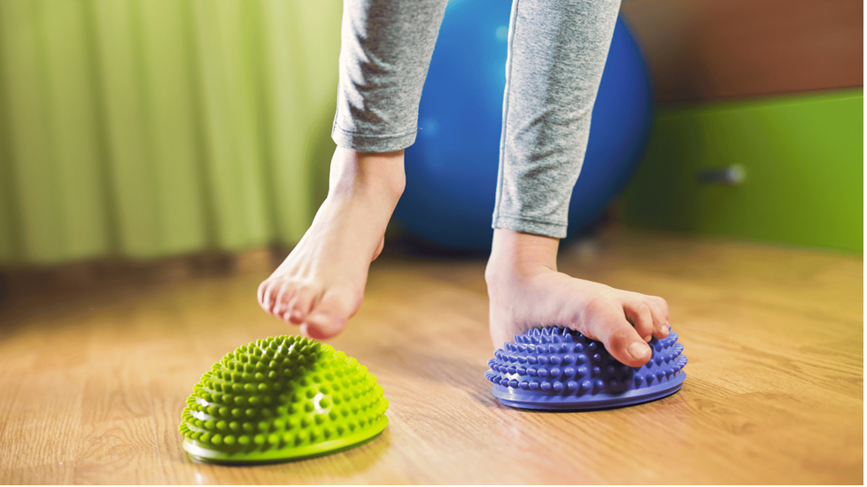 Child doing flat feet exercises for kids using balance pods to strengthen arches and improve foot alignment