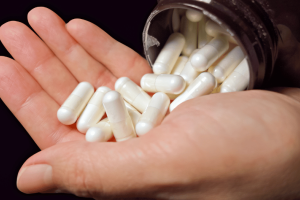 Close-up of a person holding probiotic supplement capsules poured from a bottle for gut health and digestive wellness